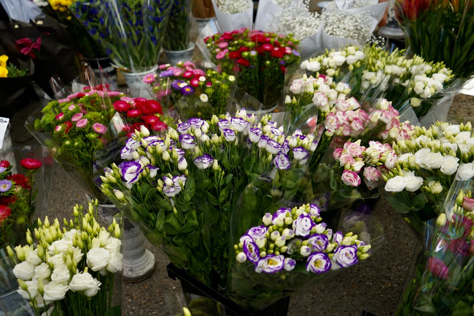 A display of fresh flower bouquets arranged on a table, featuring a variety of blooms including purple and white lisianthus, pink and white roses, red, pink, and purple chrysanthemums, and white lisia